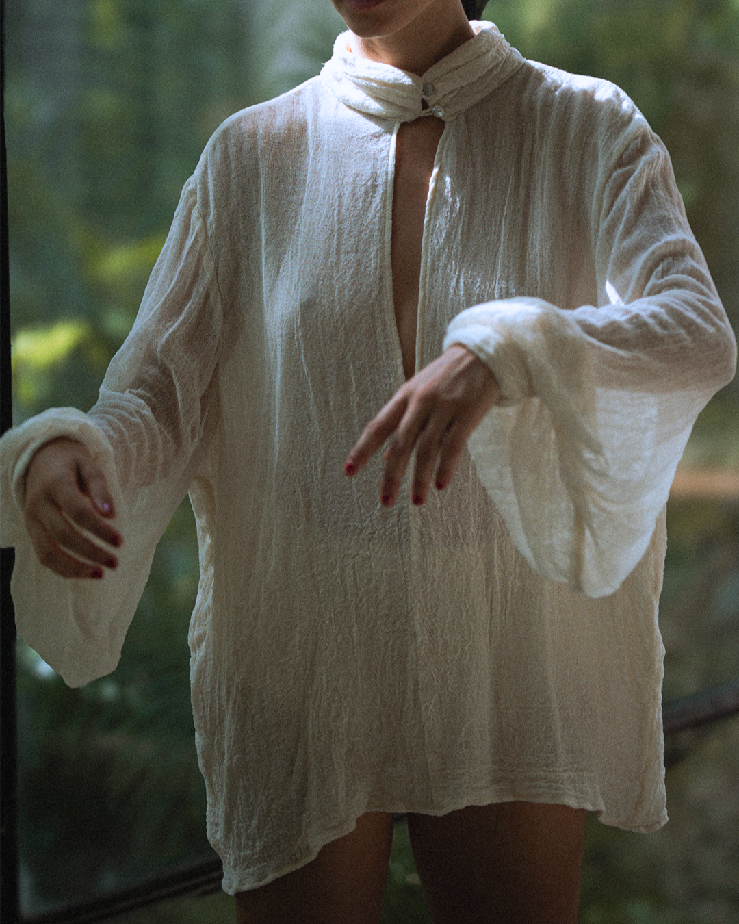 Blusa Magnolia color ivory de gasa de algodón, vista en movimiento mostrando caída y mangas.